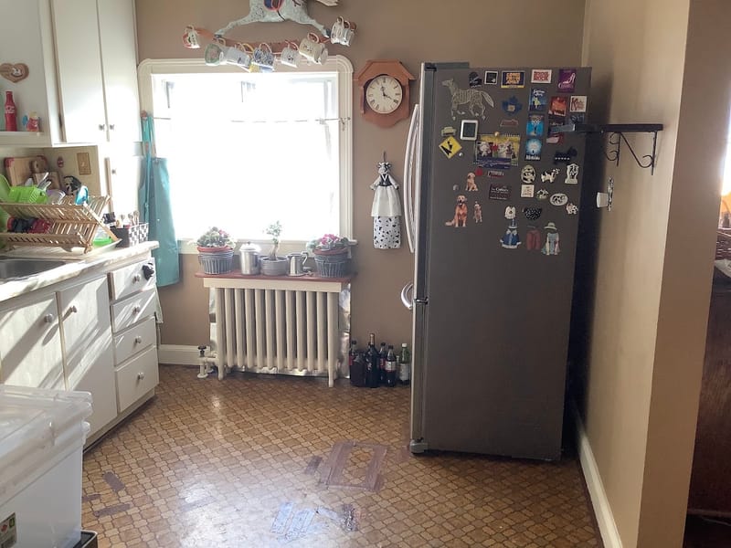 Kitchen before renovation with worn vinyl flooring