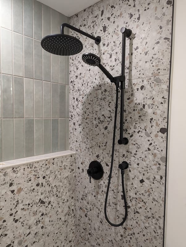 Terrazzo-tiled shower with matte black rain shower fixtures